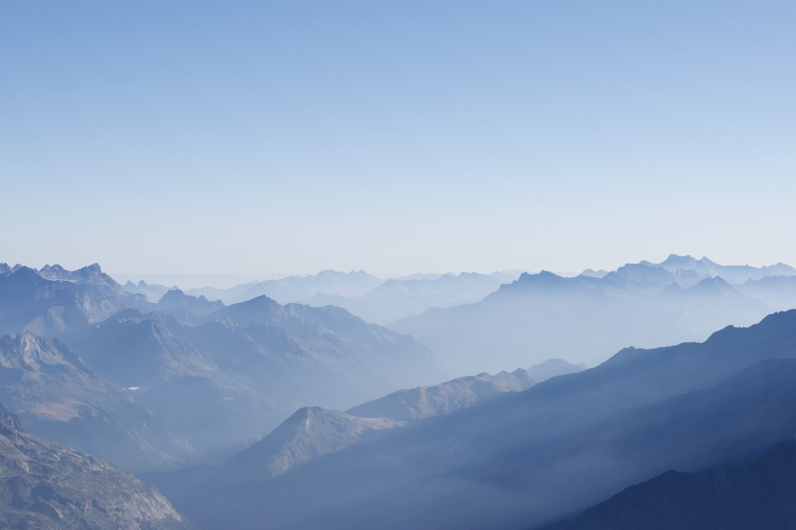 A photo of the Alps taken in summer. Haze shrouds the mountain peaks.